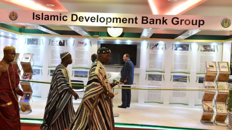 FILE - Traditional chiefs walk past an Islamic Development Bank Group stand during a meeting of the Ministers of Foreign Affairs of the Organization of Islamic Cooperation (OIC) in Abidjan, July 10, 2017.