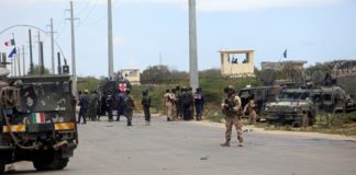 Italian and Somali security forces are seen near armored vehicles at the scene of an attack on a Italian military convoy in Mogadishu, Somalia, Sept. 30, 2019.