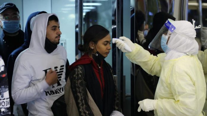 Passengers coming from China wearing masks are checked by Saudi Health Ministry employees upon their arrival at King Khalid International Airport, in Riyadh, Saudi Arabia. (Reuters
