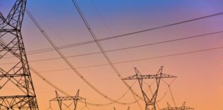 a Series of electrical transmission tower with power lines criss crossing at sunset.