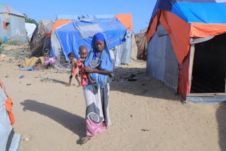 A woman carrying a child is seen at a camp on the outskirts of Mogadishu, capital of Somalia, on Jan. 13, 2022. (Xinhua/Hassan Bashi)