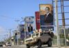 A campaign poster for presidential candidate Jamal Ahmed Ibrahim is seen above an armored vehicle belonging to Ugandan peacekeepers with the African Transition Mission in Somalia (ATMIS), on a street in Mogadishu, Somalia Tuesday, May 10, 2022. Somalia is set to hold its long-delayed presidential vote on Sunday, ending the convoluted electoral process that raised tensions in the country when the president's term expired last year without a successor in place. (AP Photo/Farah Abdi Warsameh)