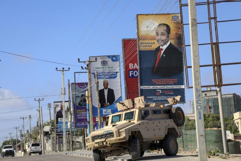A campaign poster for presidential candidate Jamal Ahmed Ibrahim is seen above an armored vehicle belonging to Ugandan peacekeepers with the African Transition Mission in Somalia (ATMIS), on a street in Mogadishu, Somalia Tuesday, May 10, 2022. Somalia is set to hold its long-delayed presidential vote on Sunday, ending the convoluted electoral process that raised tensions in the country when the president's term expired last year without a successor in place. (AP Photo/Farah Abdi Warsameh)