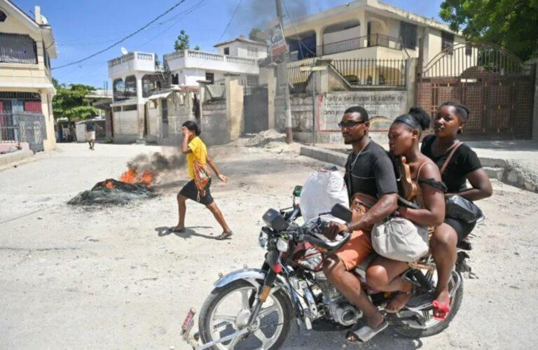 A motorcyclist passes by burning tires as people demonstrate over the rise in the cost of living in Petit-Goâve, Haiti on September 14, 2023 (Richard PIERRIN)