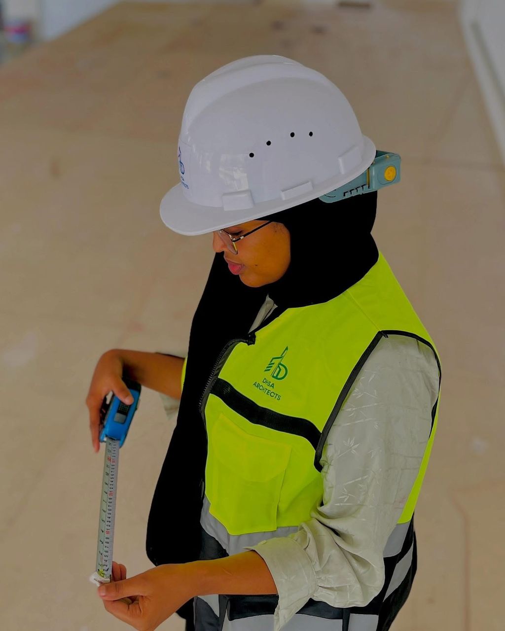 Eng. Su’ad Ali Mohamed measures site dimensions during construction supervision at a project site in Hargeisa.